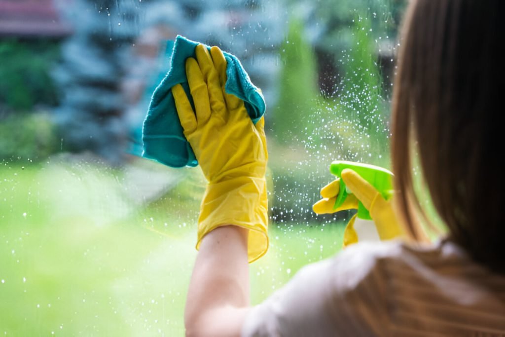 Unrecognisable woman cleaning windows of country house